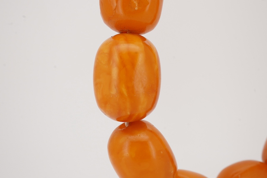 A single strand oval and barrel shaped amber bead necklace, 90cm, gross weight 102 grams. Condition - poor to fair